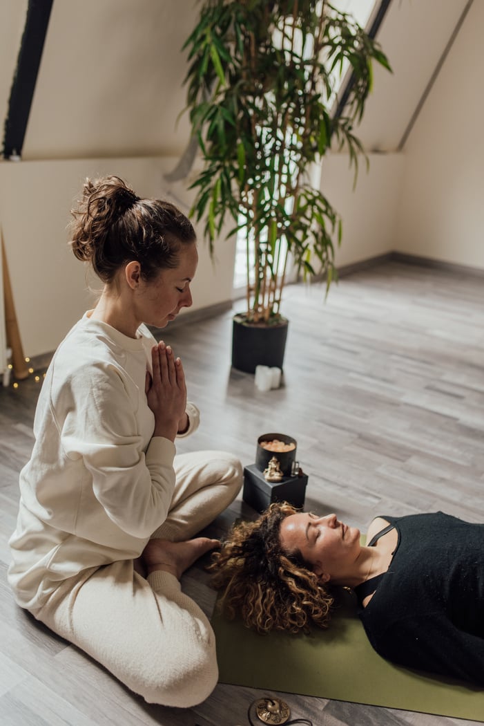 A Woman in  Yoga Position Beside a Woman Lying on Floor